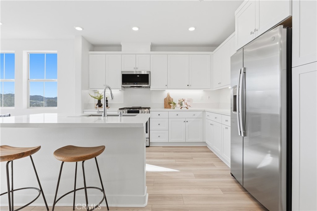 1300 Lasso Way, Unit 305 Rancho Mission Viejo, CA 92694 - Photo 6 of 75 a kitchen with stainless steel appliances granite countertop a refrigerator a stove a sink and white cabinets with wooden floor