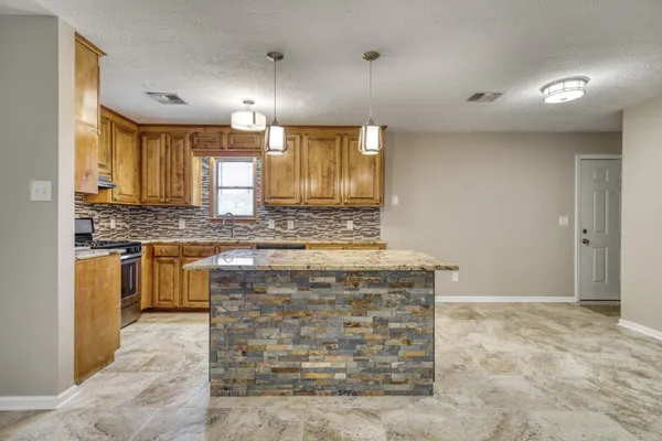 a kitchen with kitchen island granite countertop a stove a sink and a refrigerator
