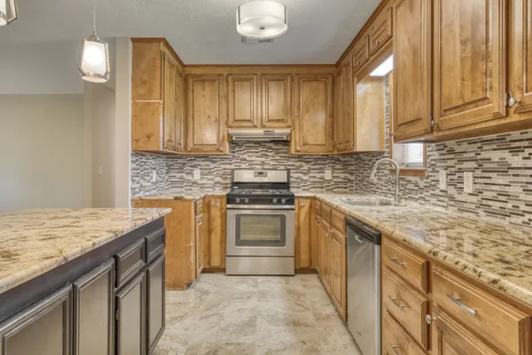 a kitchen with stainless steel appliances granite countertop a stove a sink and a white cabinets