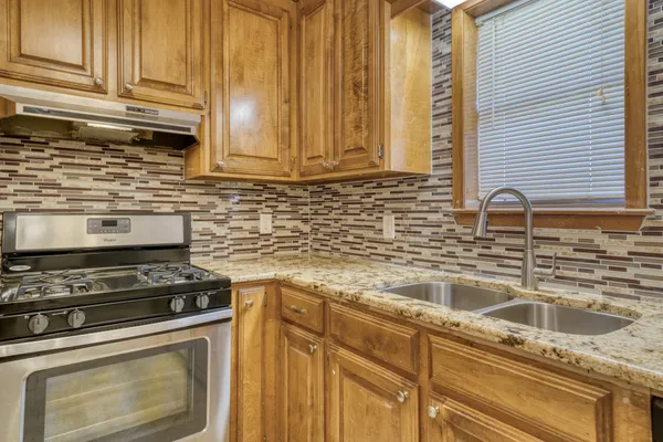 a kitchen with granite countertop a sink a stove and cabinets