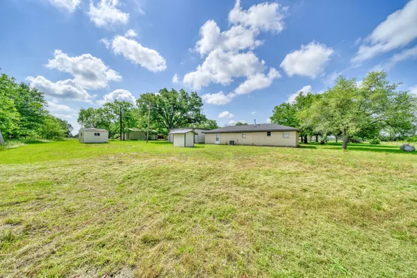 a view of a big yard with swimming pool and green space