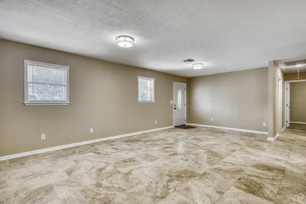 a view of an empty room with window and wooden floor