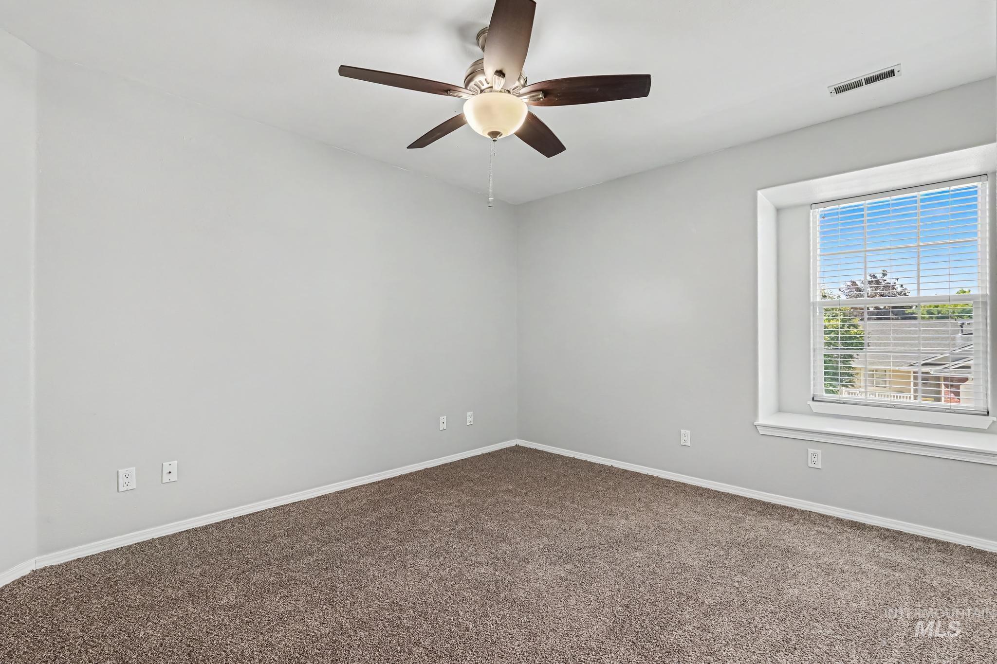 14421 West Stockwell Street Boise, ID 83713 - Photo 7 of 20 Spacious room featuring neutral carpeting, light-colored walls, and a ceiling fan with integrated lighting
