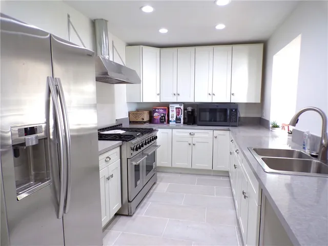 a kitchen with granite countertop a sink stainless steel appliances and cabinets