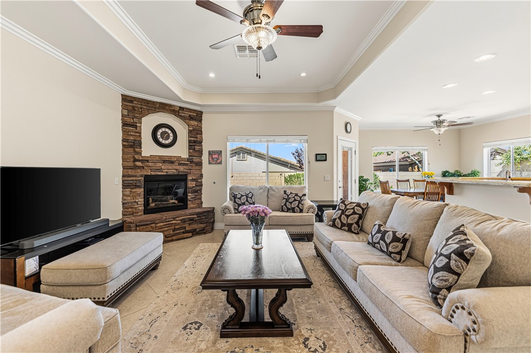 3315 Rainbow Mine Road Kingman, AZ 86401 - Photo 7 of 54 Spacious living area featuring a stacked stone fireplace, tray ceiling with recessed lighting, and a ceiling fan
