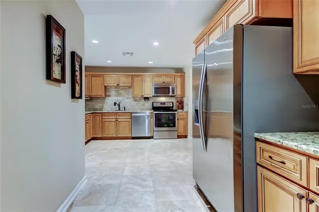 a kitchen with stainless steel appliances granite countertop a refrigerator and a stove top oven