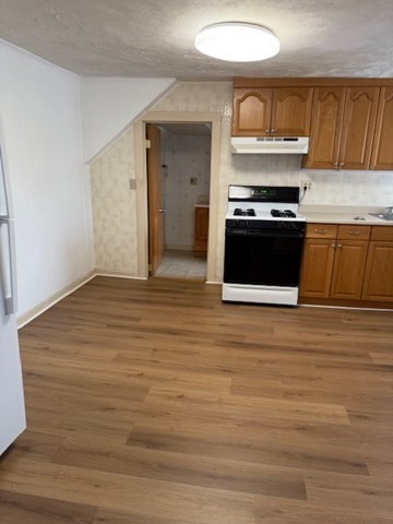 11 Elm Street, Unit 3 Ayer, MA 01432 - Photo 3 of 9 a kitchen with stainless steel appliances wooden cabinets and a stove top oven