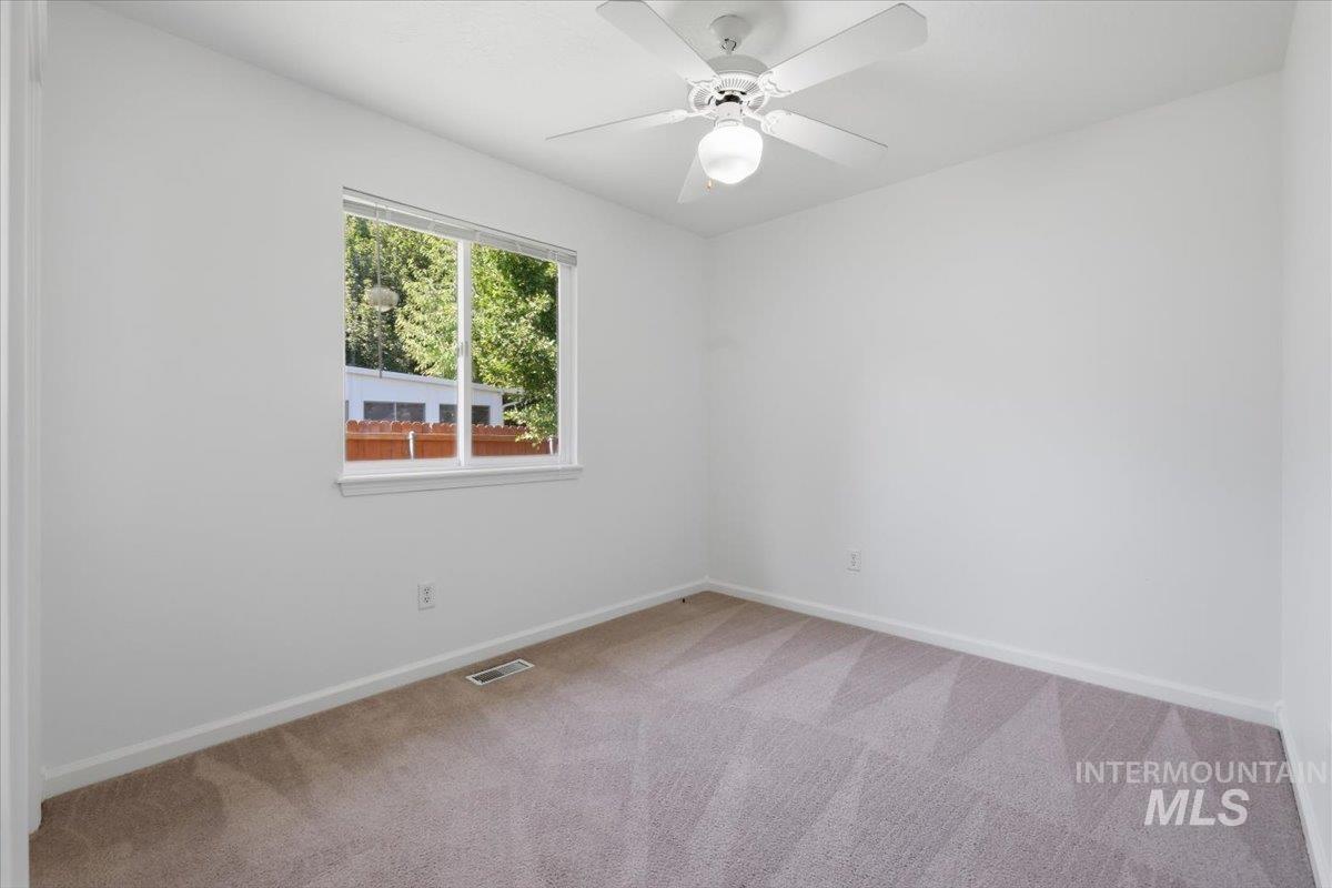 2075 North Springland Place Boise, ID 83713 - Photo 34 of 49 Bright room featuring a window with exterior foliage, a ceiling fan with integrated lighting, and neutral tone carpeting