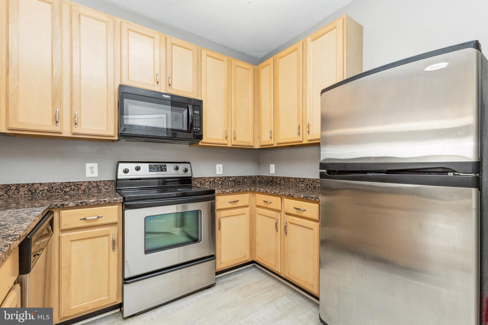 22664 Blue Elder Terrace, Unit 102 Brambleton, VA 20148 - Photo 6 of 25 a kitchen with stainless steel appliances granite countertop a stove a sink and a microwave