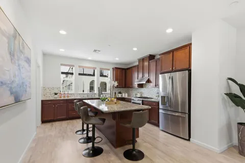 a kitchen with stainless steel appliances a refrigerator a sink a stove a dining table and chairs