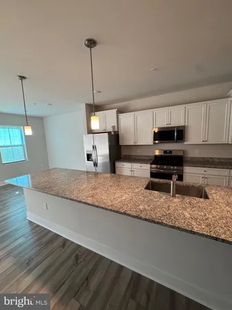 a kitchen with stainless steel appliances granite countertop a sink a stove and a wooden floors