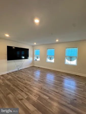 a view of an empty room with wooden floor and windows
