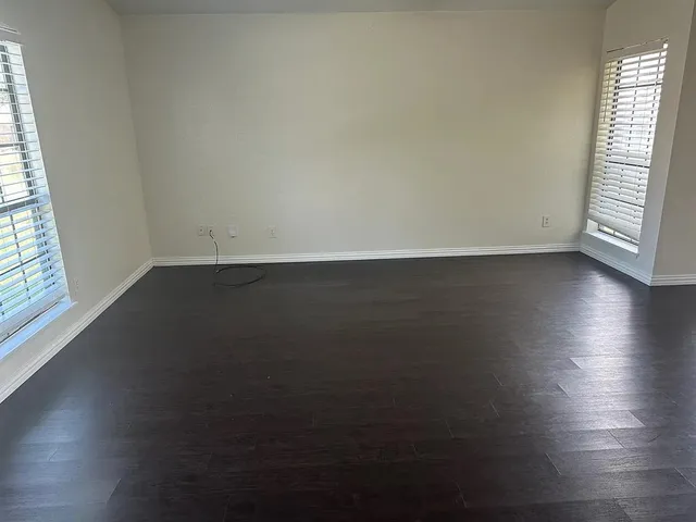 an empty room with wooden floor and windows in it