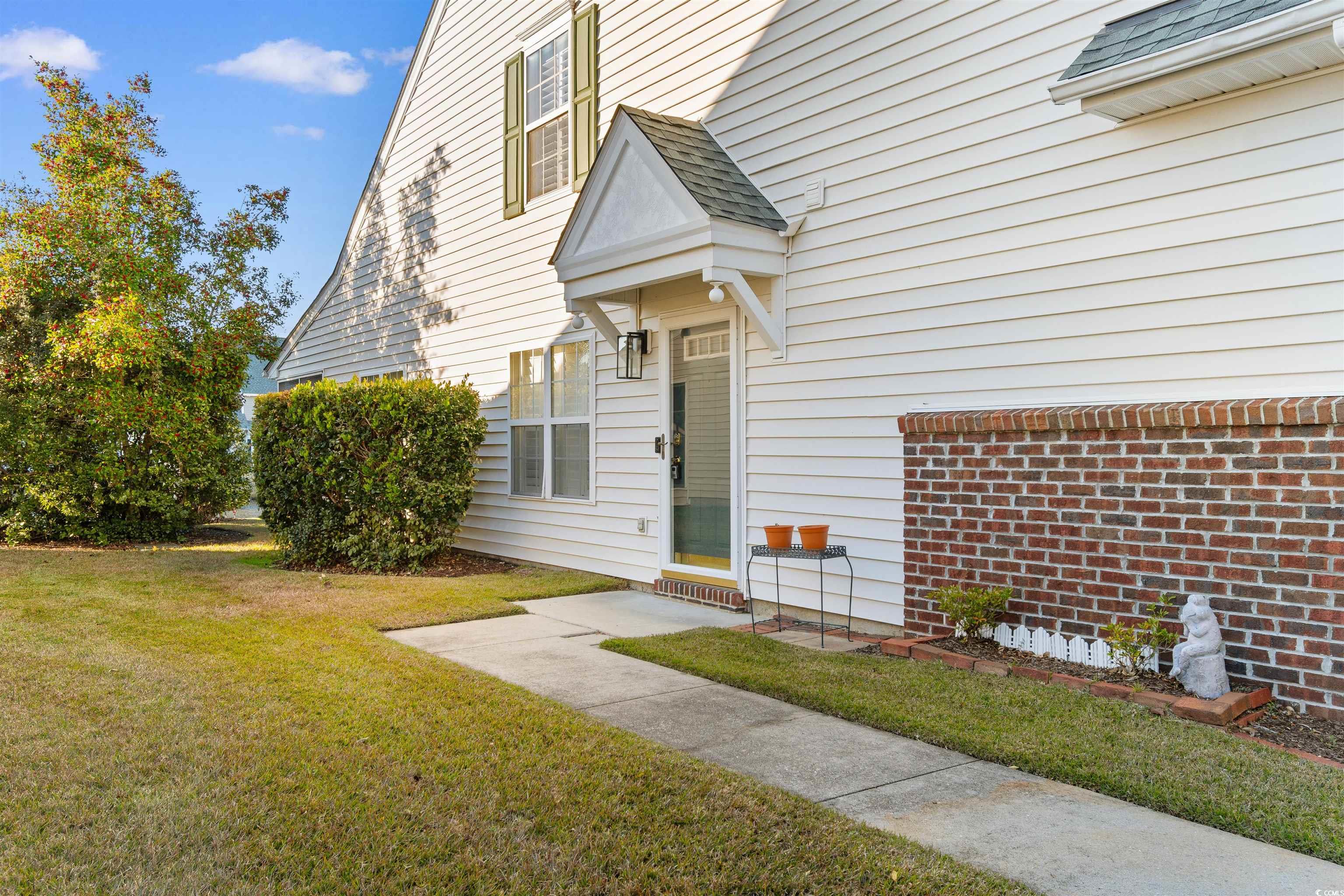 153 Wimbledon Way, Unit 153 Murrells Inlet, SC 29576 - Photo 3 of 32 View of exterior entry featuring a shingled roof and a lawn