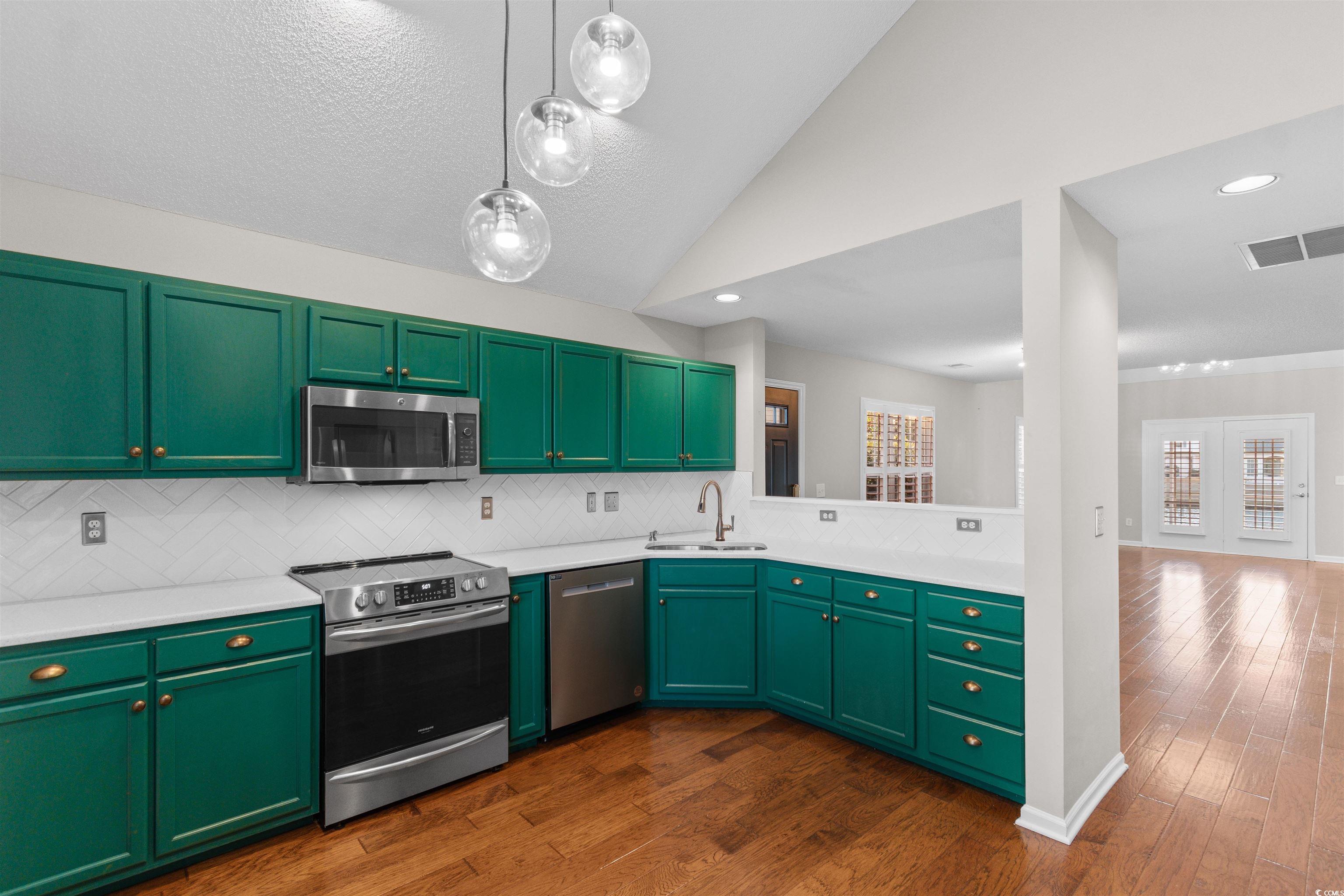 153 Wimbledon Way, Unit 153 Murrells Inlet, SC 29576 - Photo 5 of 32 Kitchen featuring green cabinets, stainless steel appliances, vaulted ceiling, dark wood-style flooring, and recessed lighting