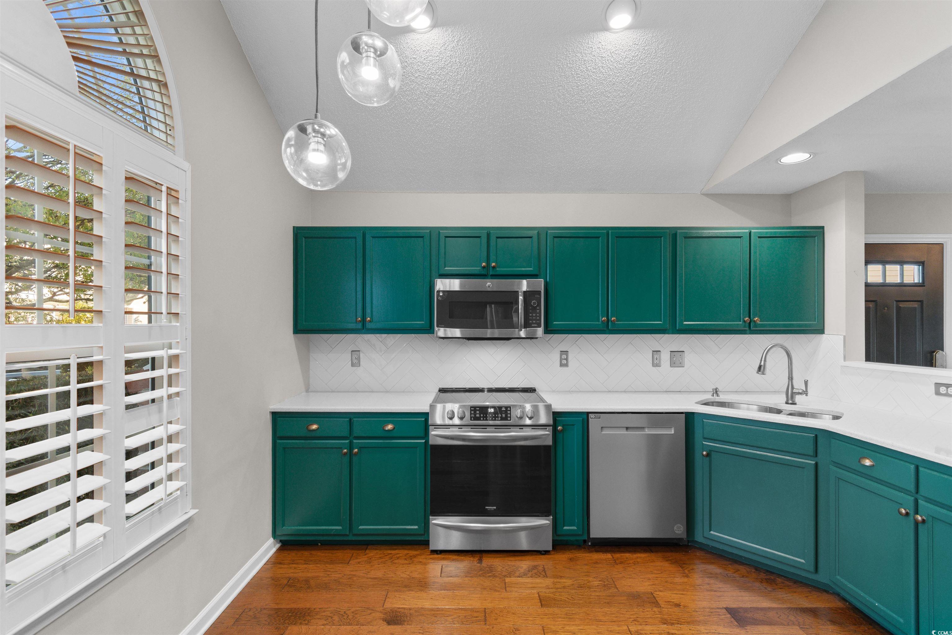 153 Wimbledon Way, Unit 153 Murrells Inlet, SC 29576 - Photo 7 of 32 Kitchen with green cabinetry, vaulted ceiling, stainless steel appliances, hanging light fixtures, and dark wood finished floors