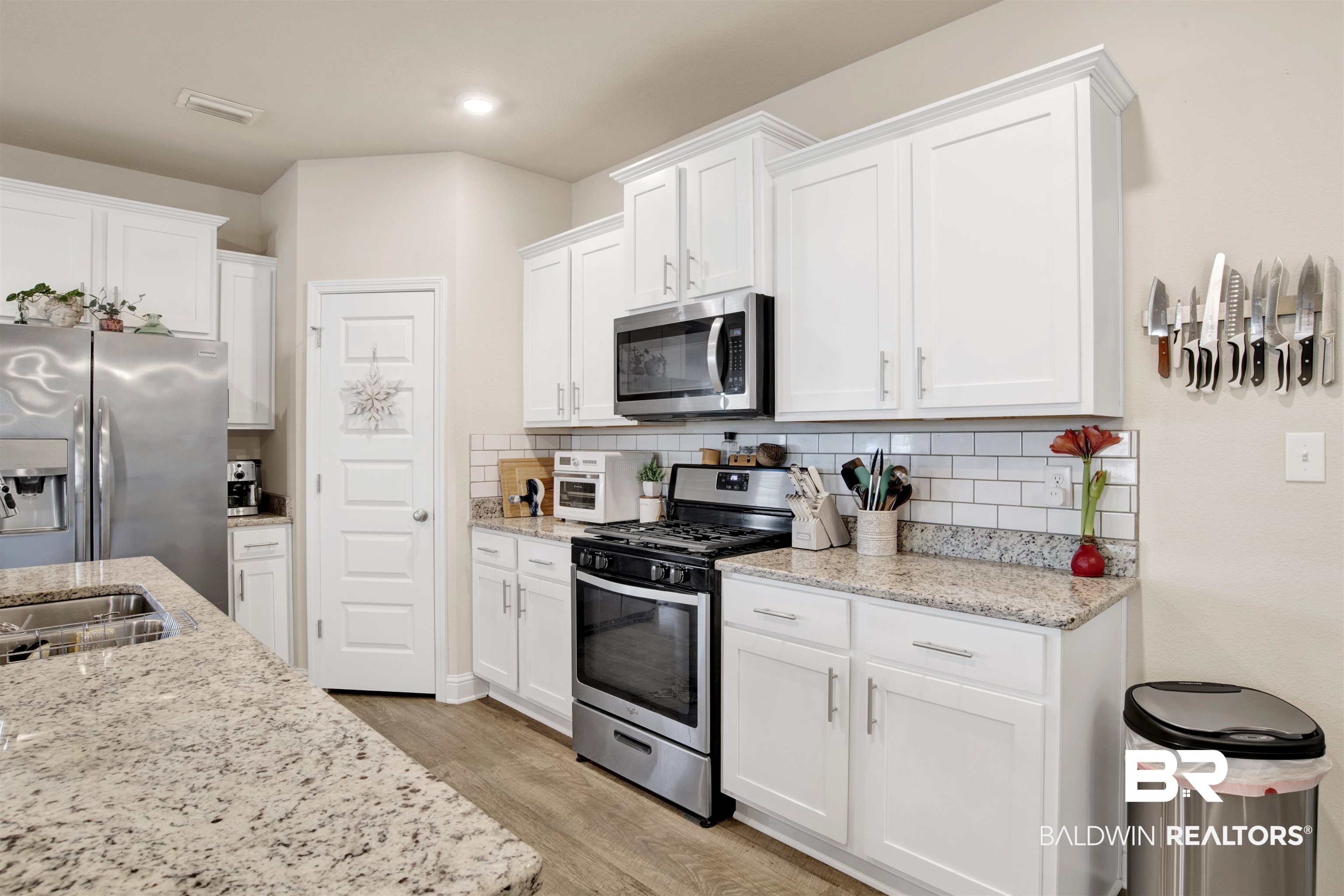 9622 Volterra Avenue Daphne, AL 36526 - Photo 3 of 31 Kitchen with decorative backsplash, stainless steel appliances, white cabinetry, and light hardwood / wood-style flooring
