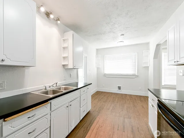 a kitchen with granite countertop a sink cabinets wooden floor and stainless steel appliances