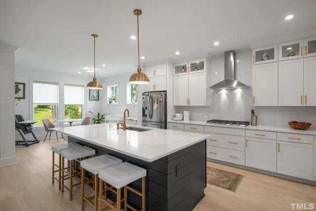 a kitchen with stainless steel appliances granite countertop a stove a sink a oven a dining table and chairs with wooden floor