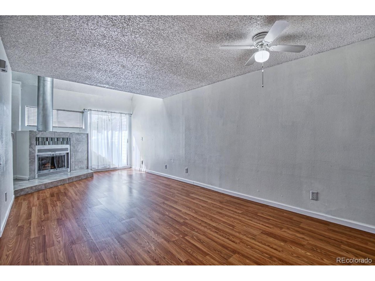 8701 Huron Street, Unit 209 Thornton, CO 80260 - Photo 4 of 25 a view of an empty room with a fireplace and wooden floor