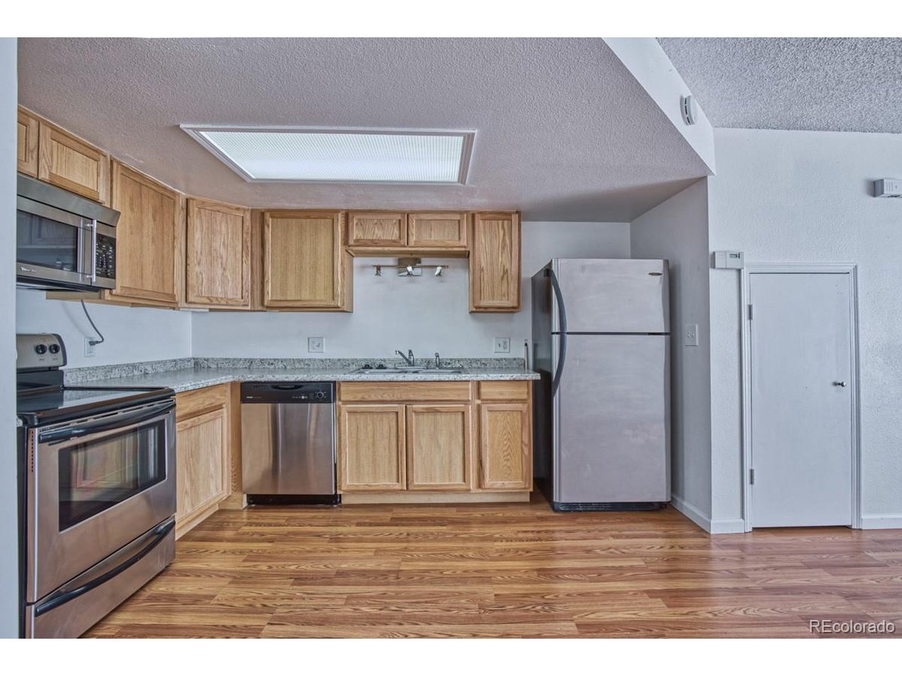 8701 Huron Street, Unit 209 Thornton, CO 80260 - Photo 8 of 25 a kitchen with granite countertop a refrigerator and a stove top oven
