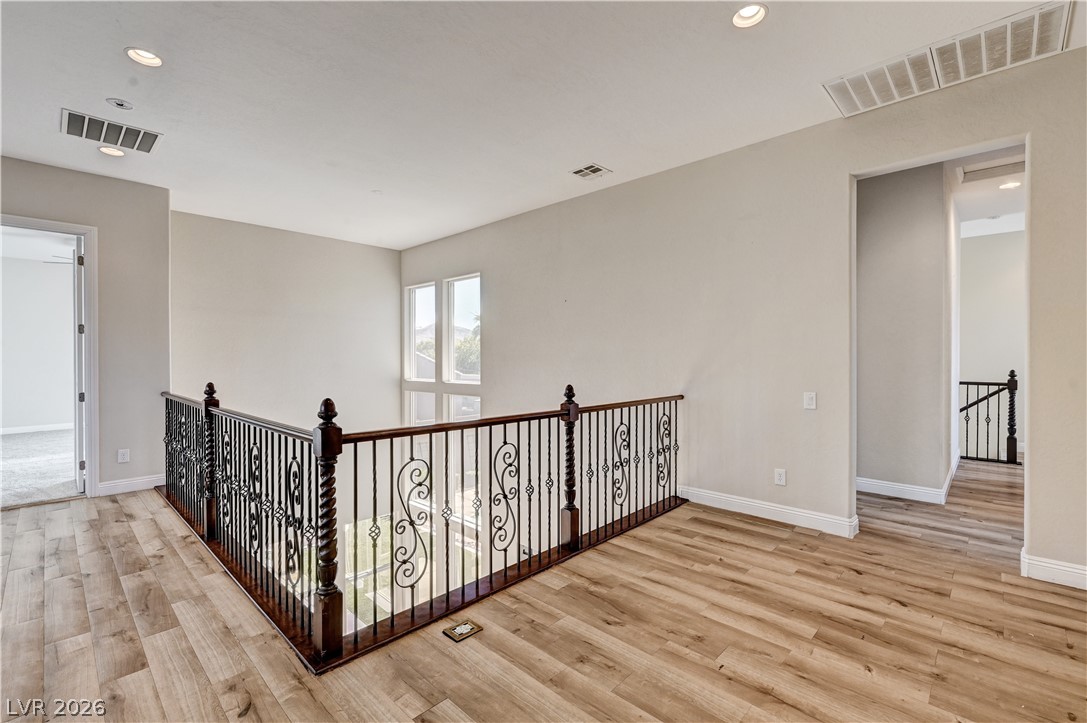2793 Rosenhearty Drive Henderson, NV 89044 - Photo 54 of 85 An inviting upstairs landing features light-toned hardwood flooring and an ornate wrought-iron railing overlooking a lower level.