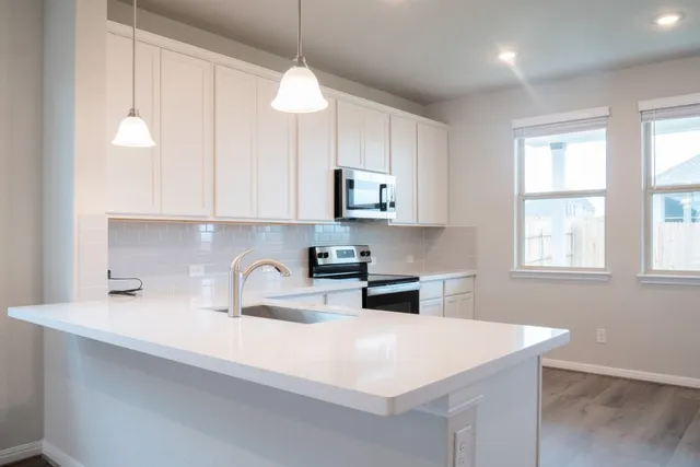 a kitchen with stainless steel appliances a sink a stove a microwave and cabinets