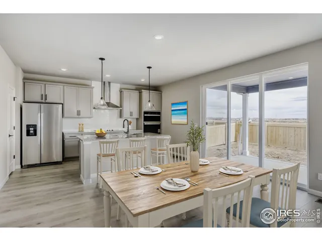 a kitchen with stainless steel appliances kitchen island granite countertop a table chairs and a refrigerator