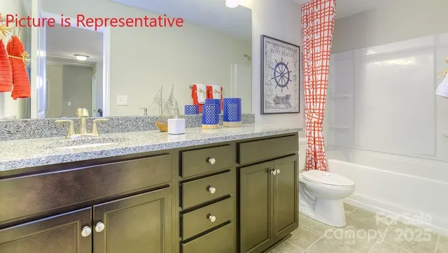 a bathroom with a granite countertop sink mirror vanity and toilet