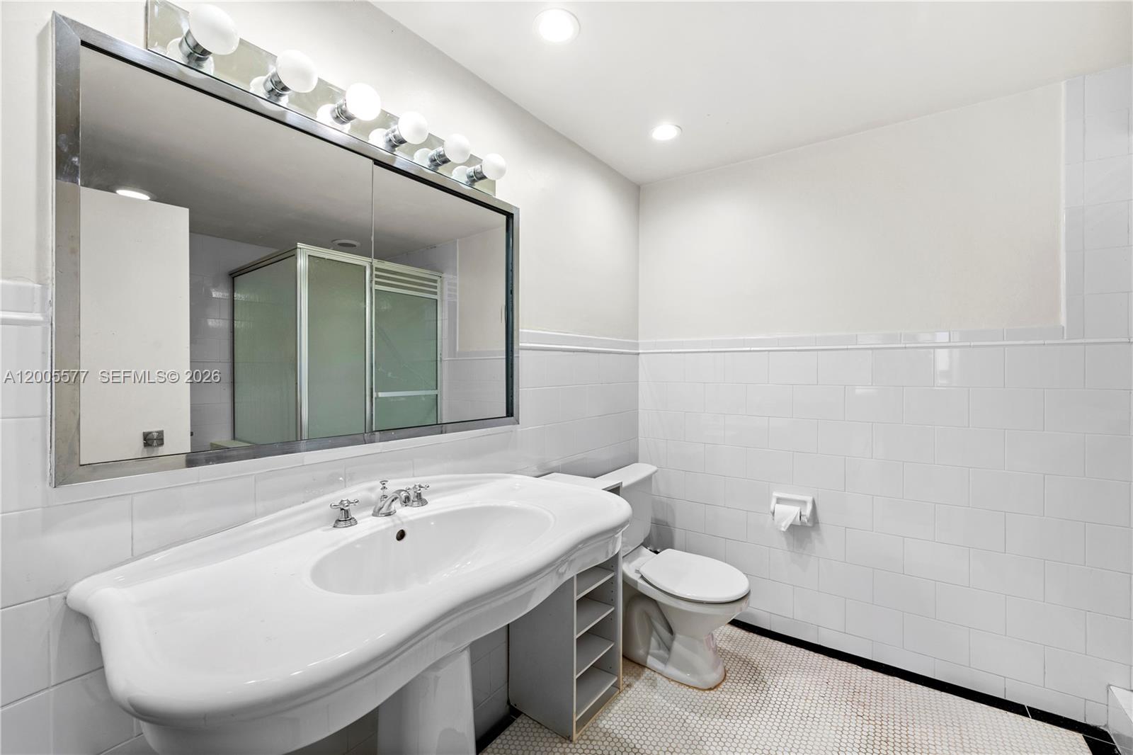 5255 Collins Avenue, Unit 11A Miami Beach, FL 33140 - Photo 6 of 15 a bathroom with a toilet sink and mirror