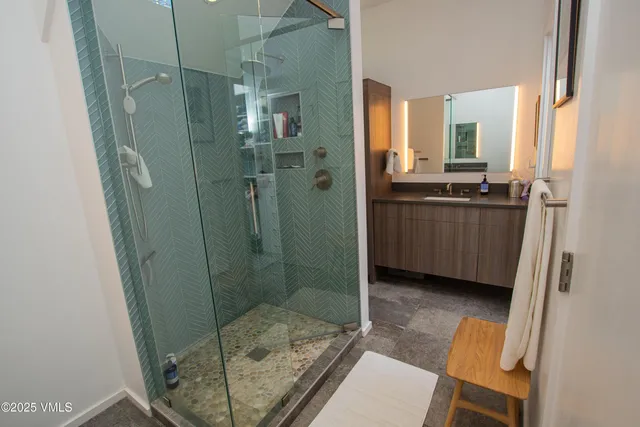 a bathroom with a granite countertop shower a sink and a mirror