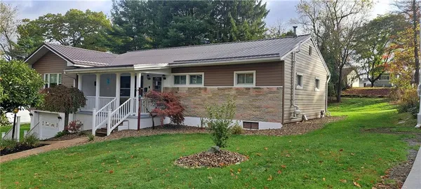a view of a house with a yard and a large tree