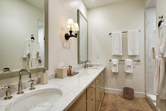 a bathroom with double vanity sinks and a shower