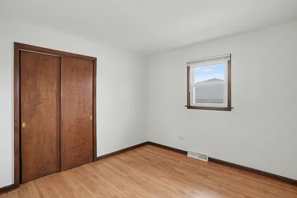 a view of an empty room with wooden floor and closet