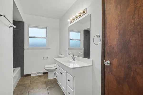 a bathroom with a double vanity sink a mirror and a toilet
