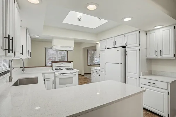 a kitchen with refrigerator a stove and white cabinets