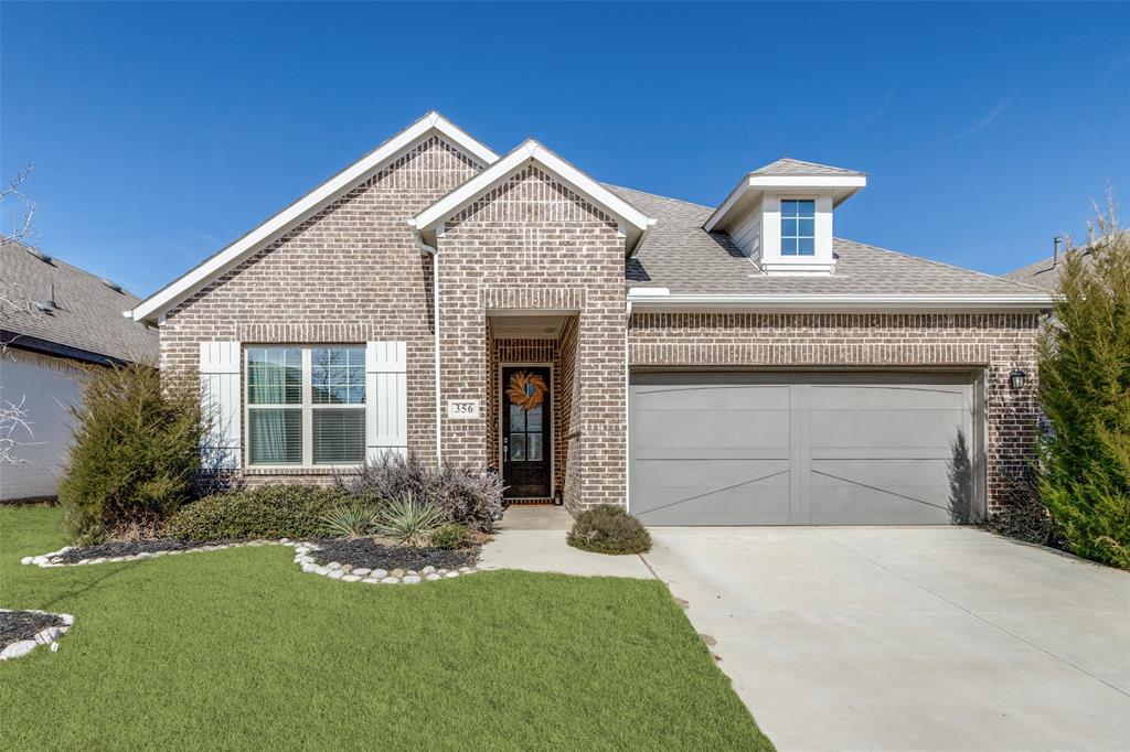 View of front of home featuring brick siding, a front lawn, roof with shingles, concrete driveway, and a garage