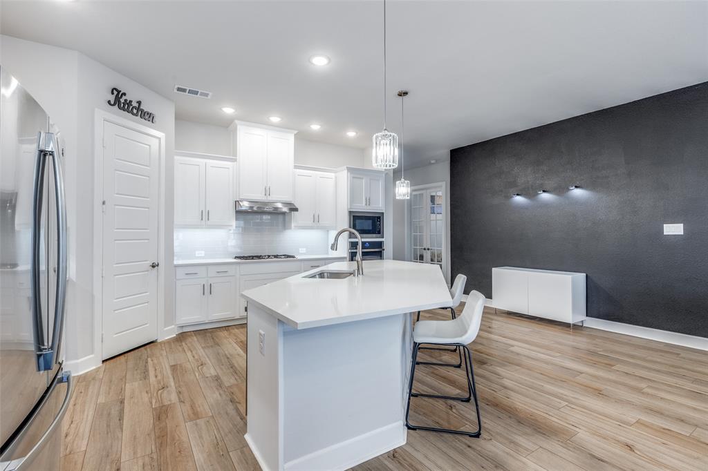 356 Greenbriar Road Little Elm, TX 75068 - Photo 11 of 25 Kitchen with white cabinetry, hanging light fixtures, stainless steel appliances, and light wood-style flooring
