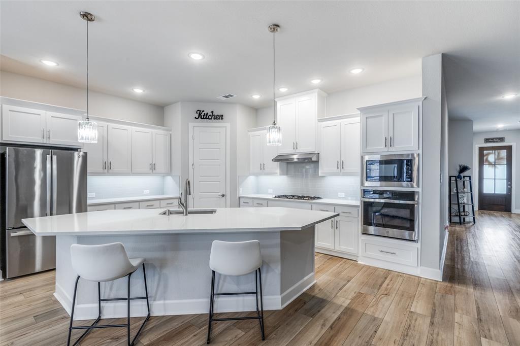 356 Greenbriar Road Little Elm, TX 75068 - Photo 12 of 25 Kitchen with stainless steel appliances, white cabinets, light wood finished floors, and tasteful backsplash