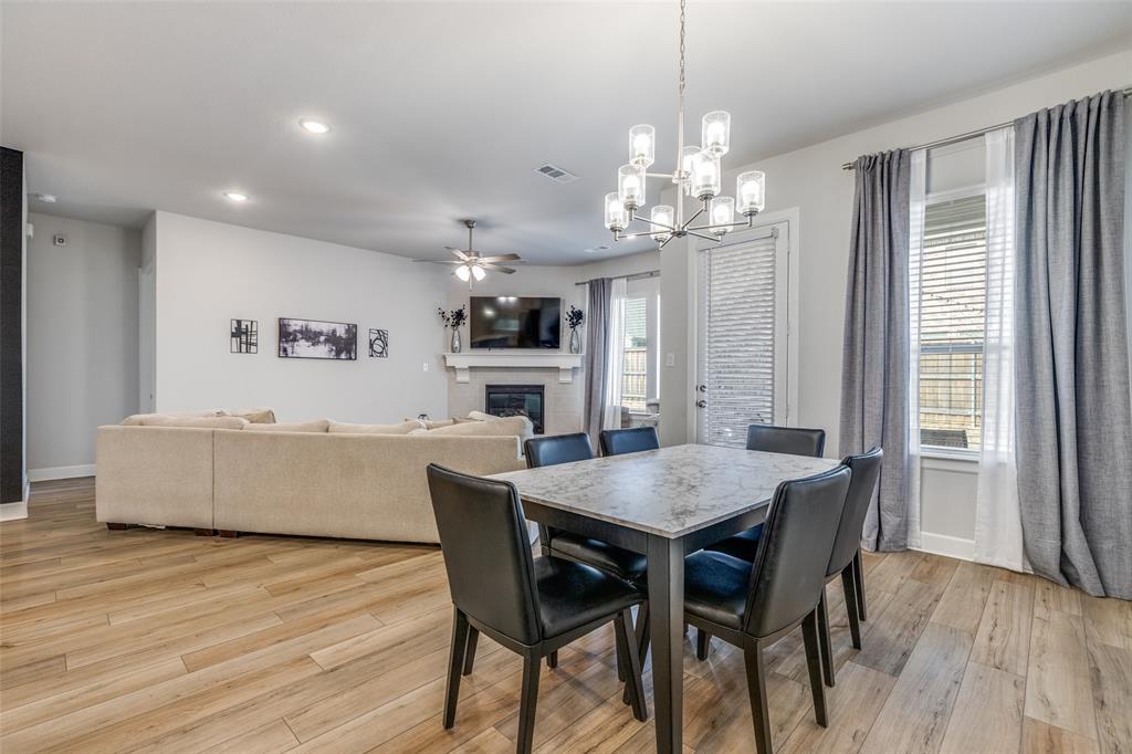 356 Greenbriar Road Little Elm, TX 75068 - Photo 15 of 25 Dining space with a glass covered fireplace, light wood-style floors, hanging lights, and a ceiling fan