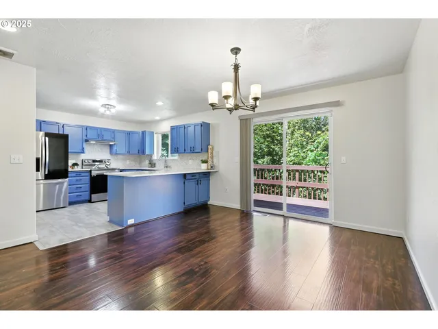 a open kitchen with stainless steel appliances granite countertop a refrigerator a stove a sink dishwasher and white cabinets with wooden floor