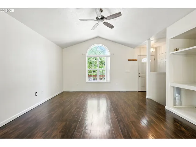 a view of an empty room with a window and wooden floor
