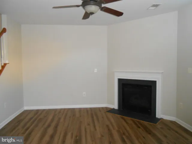 a view of empty room with wooden floor and fireplace