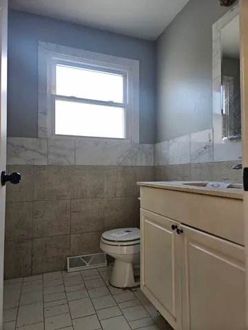 a bathroom with a granite countertop toilet a sink a mirror and a window