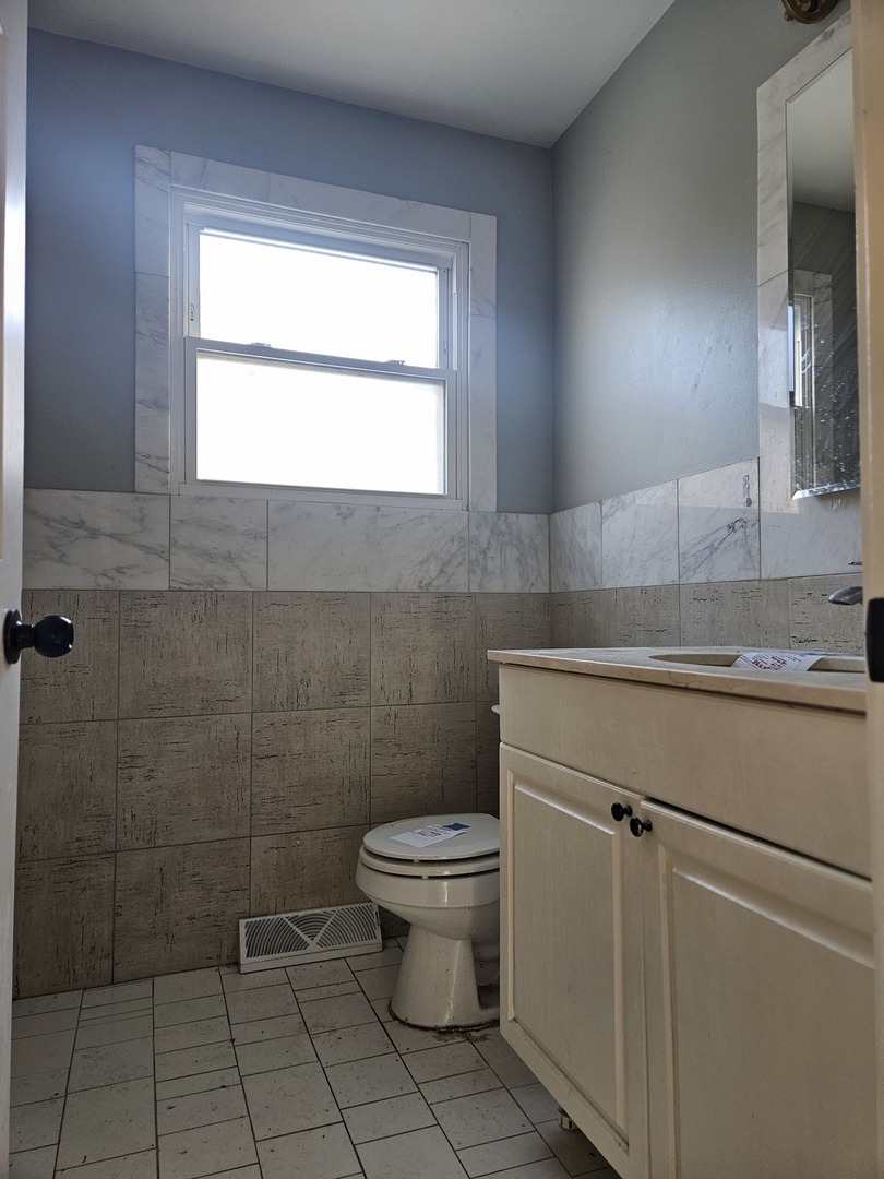 6732 South Peoria Street Chicago, IL 60621 - Photo 20 of 22 a bathroom with a granite countertop toilet a sink a mirror and a window