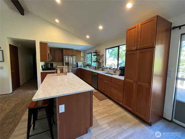 a kitchen with stainless steel appliances granite countertop a refrigerator a sink dishwasher a stove with wooden cabinets and wooden floor