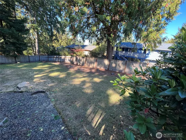 a view of yard with tree and wooden fence
