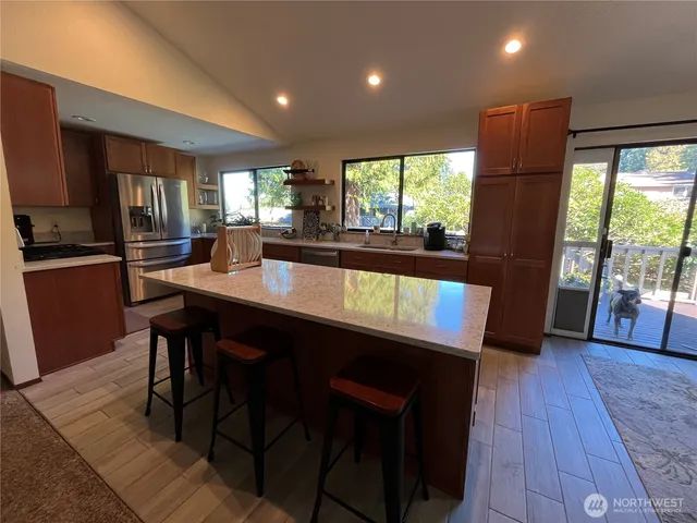 a kitchen with a table chairs refrigerator and wooden floor