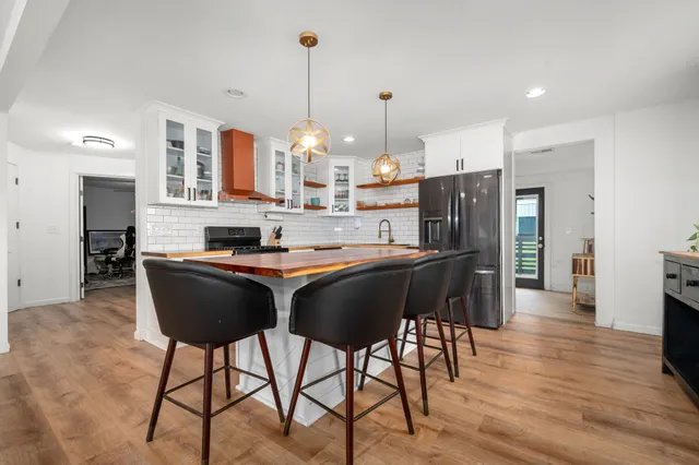 a living room with stainless steel appliances kitchen island granite countertop furniture and a wooden floor