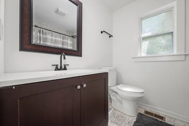 a bathroom with a sink mirror toilet and next to a window